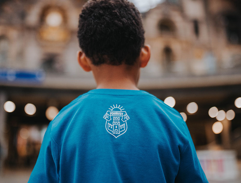 Close-up van het logo van Tourist op een blauwe T-shirt.