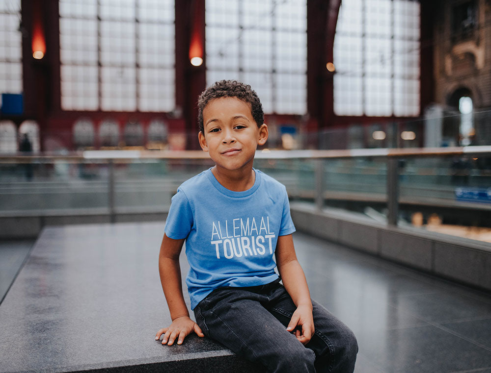 Jongen met blauwe T-shirt met opdruk ALLEMAALTOURIST.